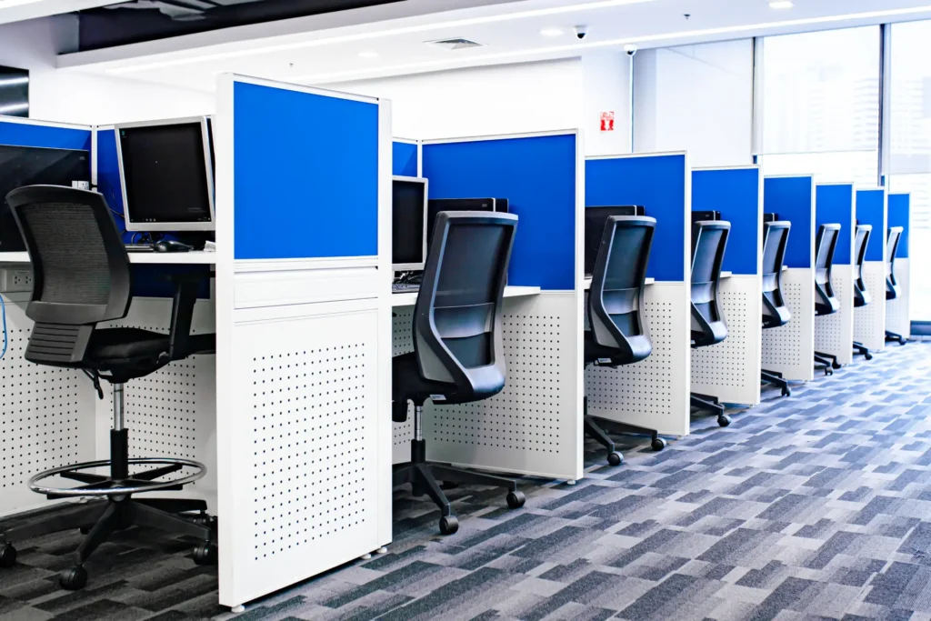 Organized office cubicle layout with blue partitions, ergonomic chairs, computers, and natural light — CXbuildr office design and construction services.